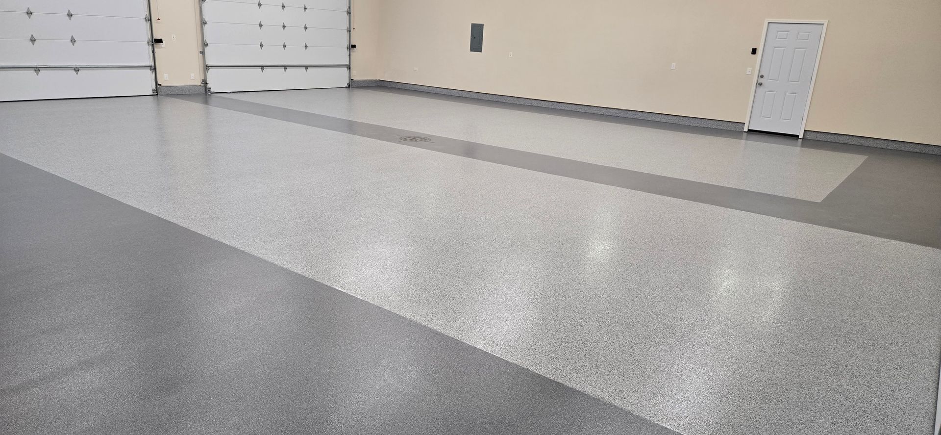 Empty indoor garage with speckled gray floor and beige walls