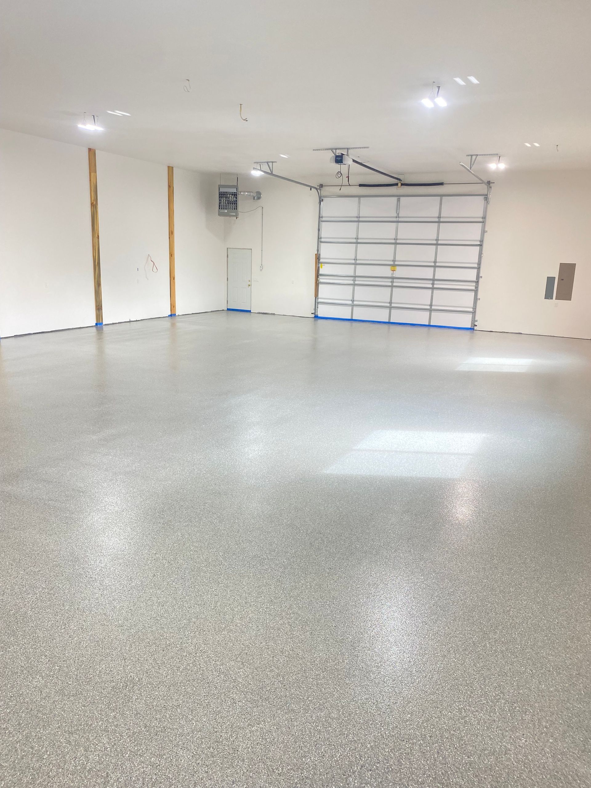 Empty white garage with a speckled epoxy floor and a closed garage door at the back.