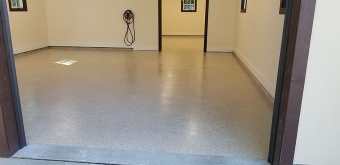 Empty beige room with speckled gray floor and open doorway in the center