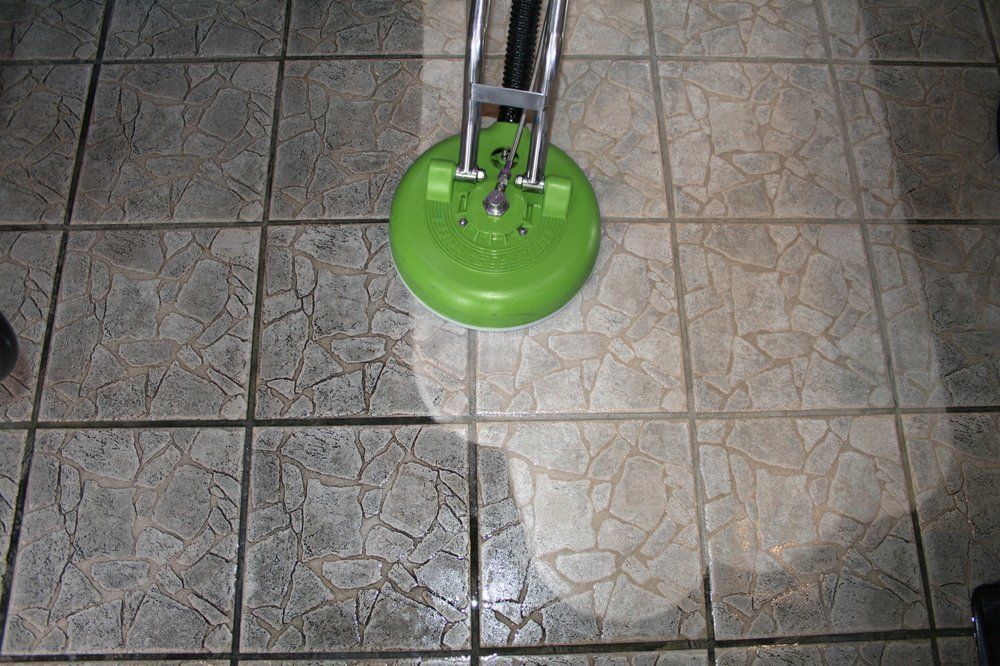 Green floor-cleaning machine on tiled floor, casting a bright circular light.