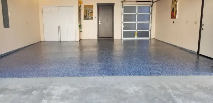 Empty garage with blue speckled floor and white double doors at the back