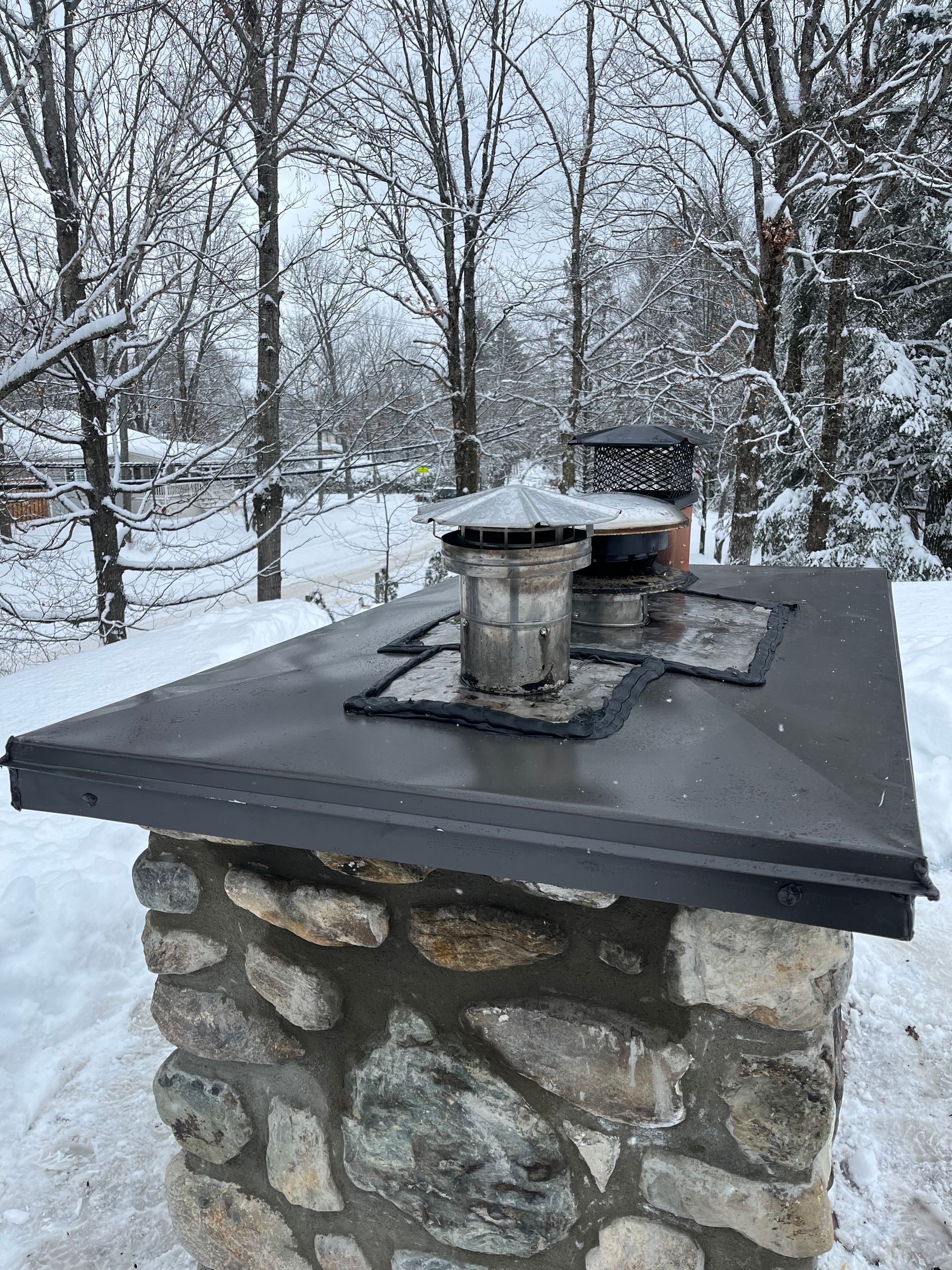 Une cheminée posée au sommet d'un pilier en pierre dans la neige.