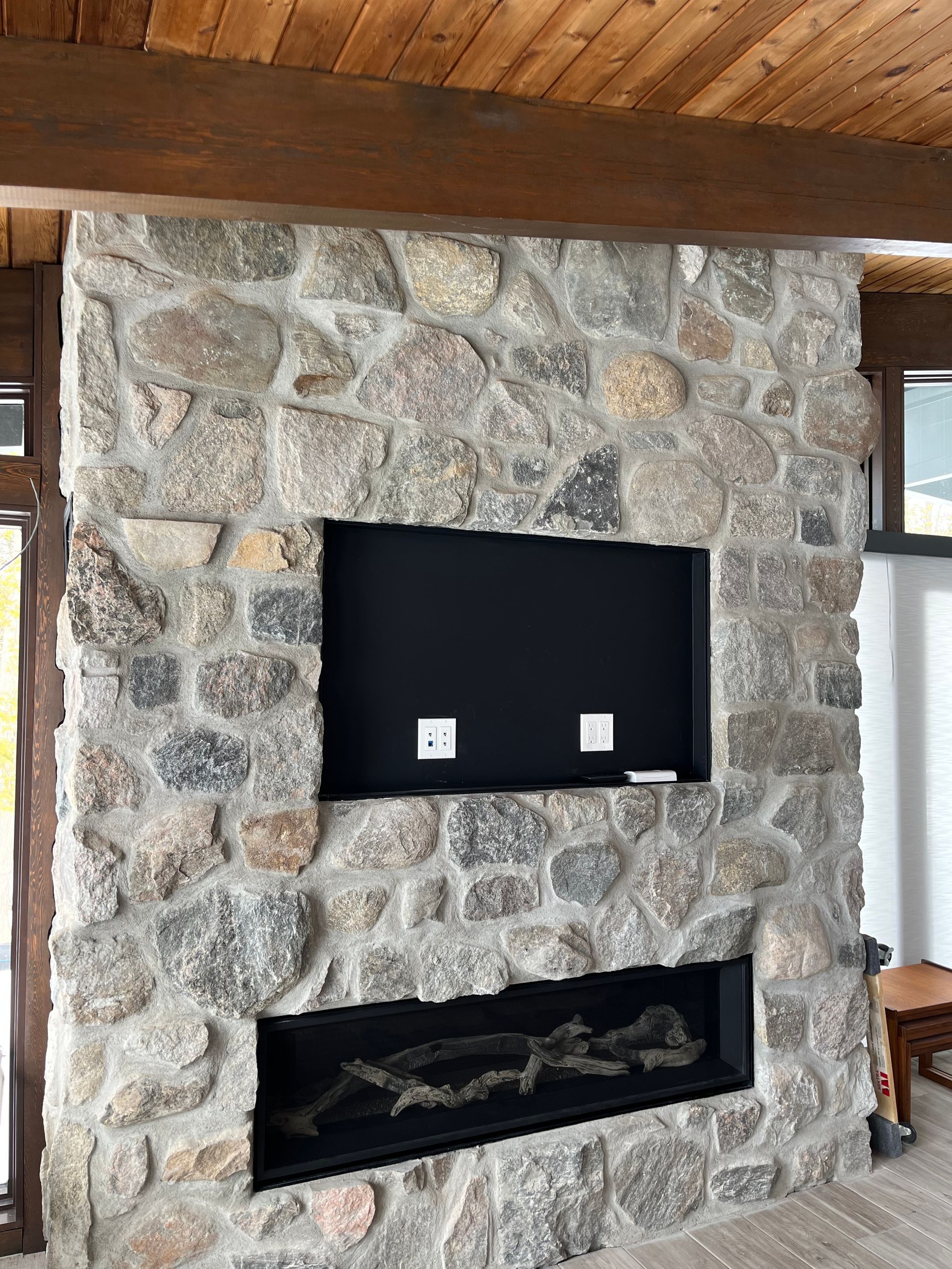 Une cheminée en pierre avec une télévision à écran plat intégrée.