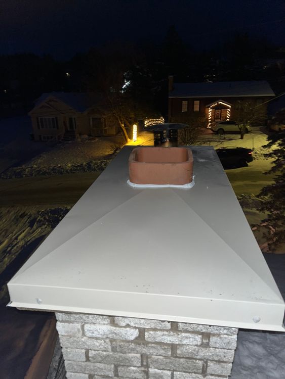 La nuit, une cheminée en brique se trouve au sommet d'un toit.