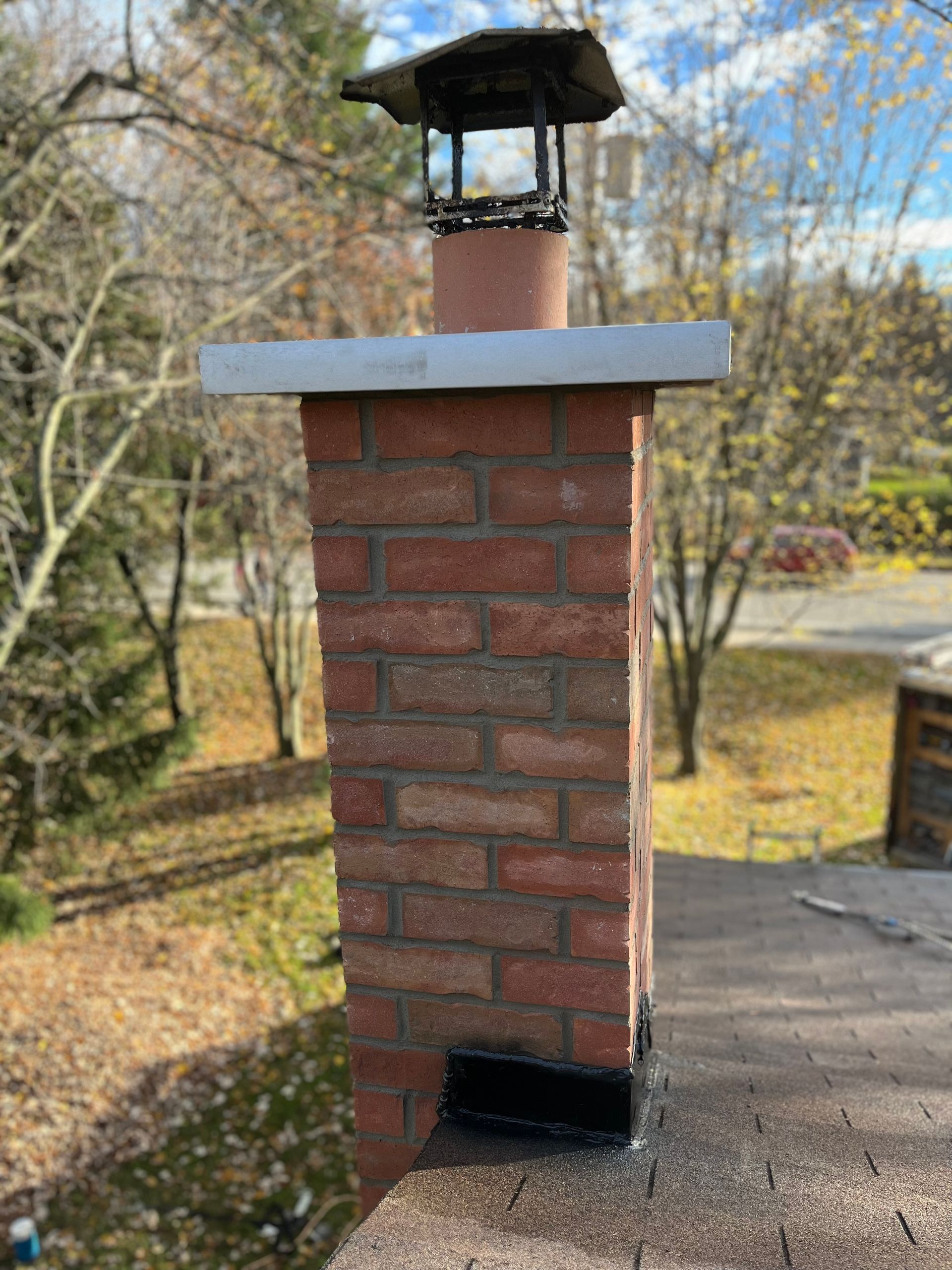 Une cheminée en brique se trouve au sommet d’un toit.