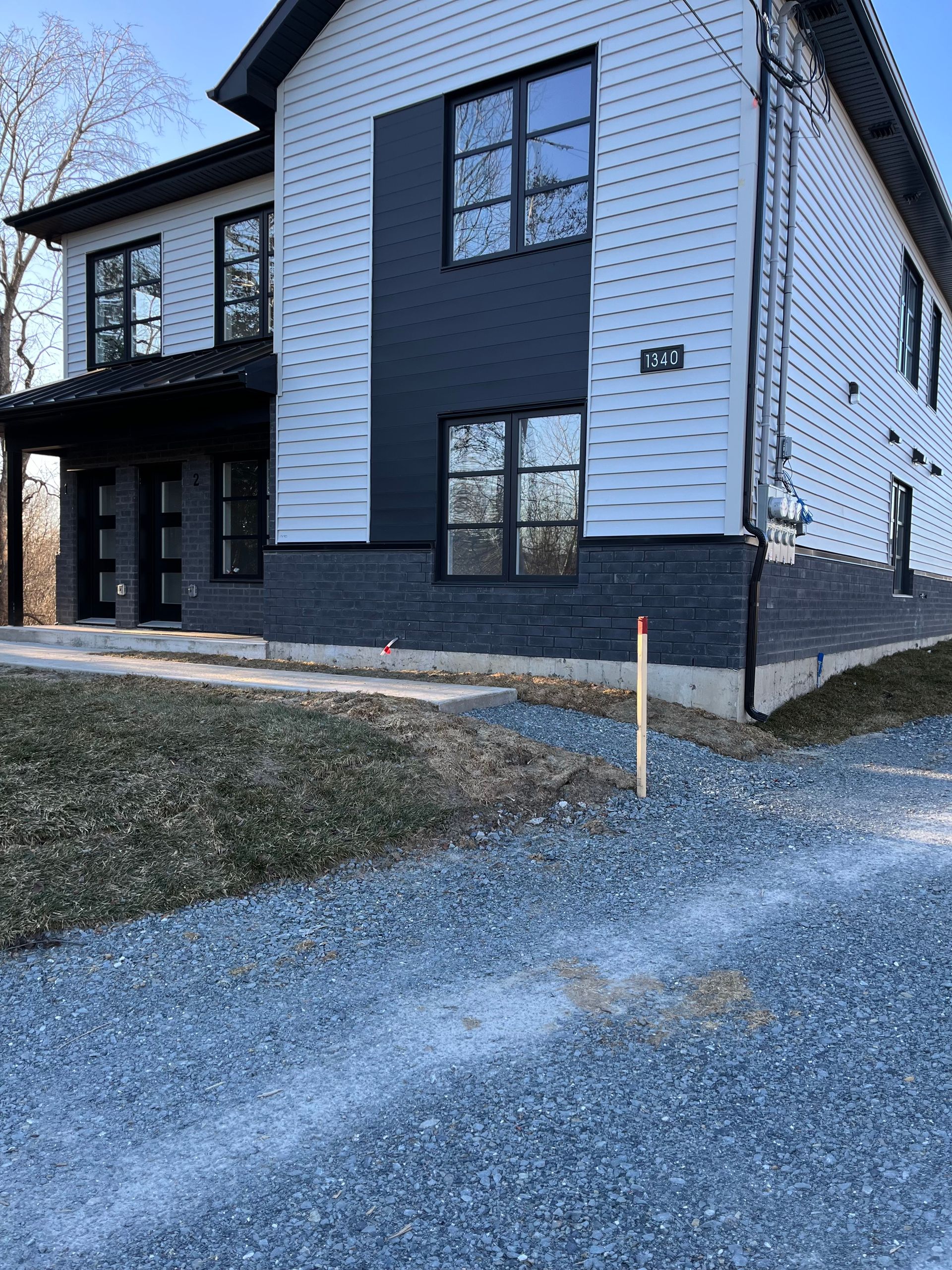Une maison blanche et noire avec une allée de gravier devant elle