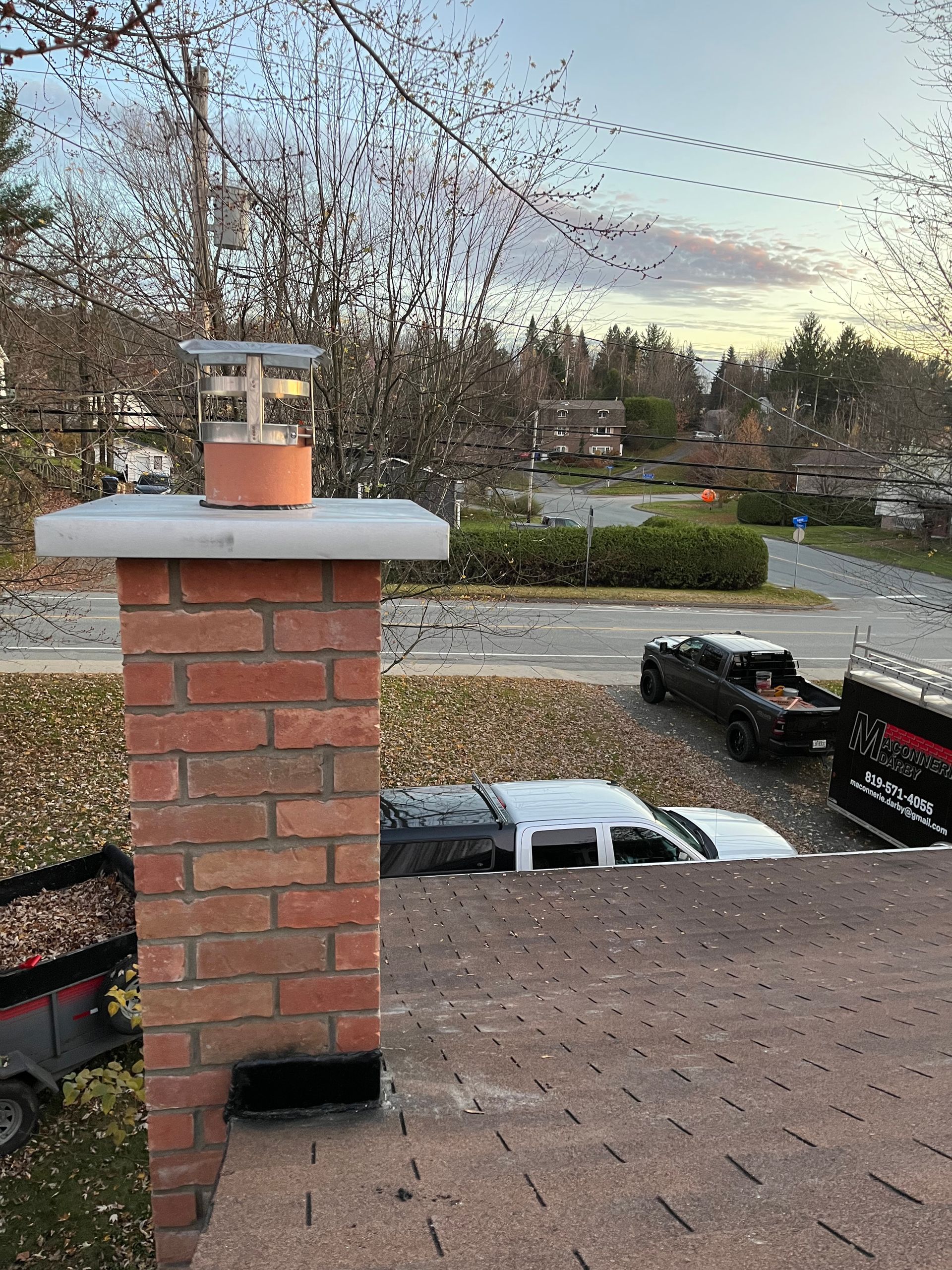 Une cheminée en brique se trouve au sommet d’un toit à côté d’un camion.