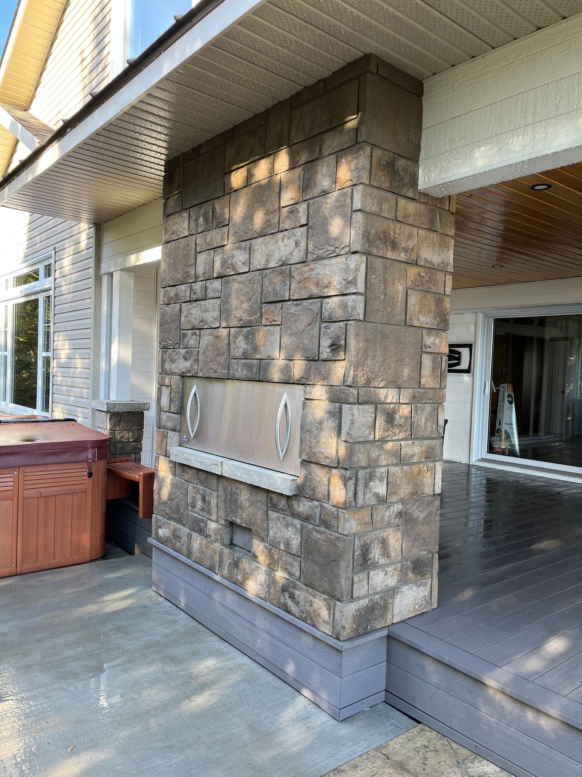 Un mur en pierre avec une grille en acier inoxydable se trouve sur le côté d'une maison.