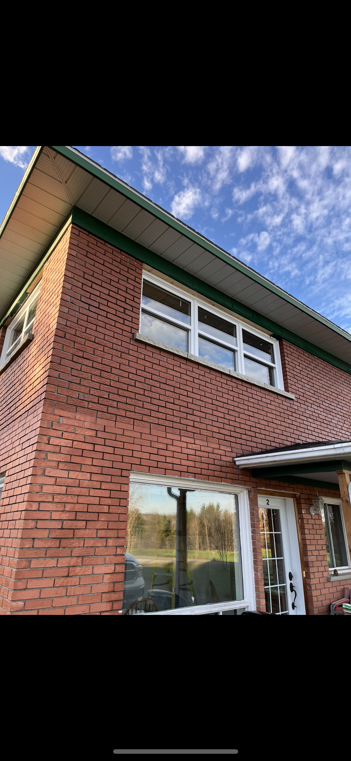 Un bâtiment en brique avec un toit vert et beaucoup de fenêtres.