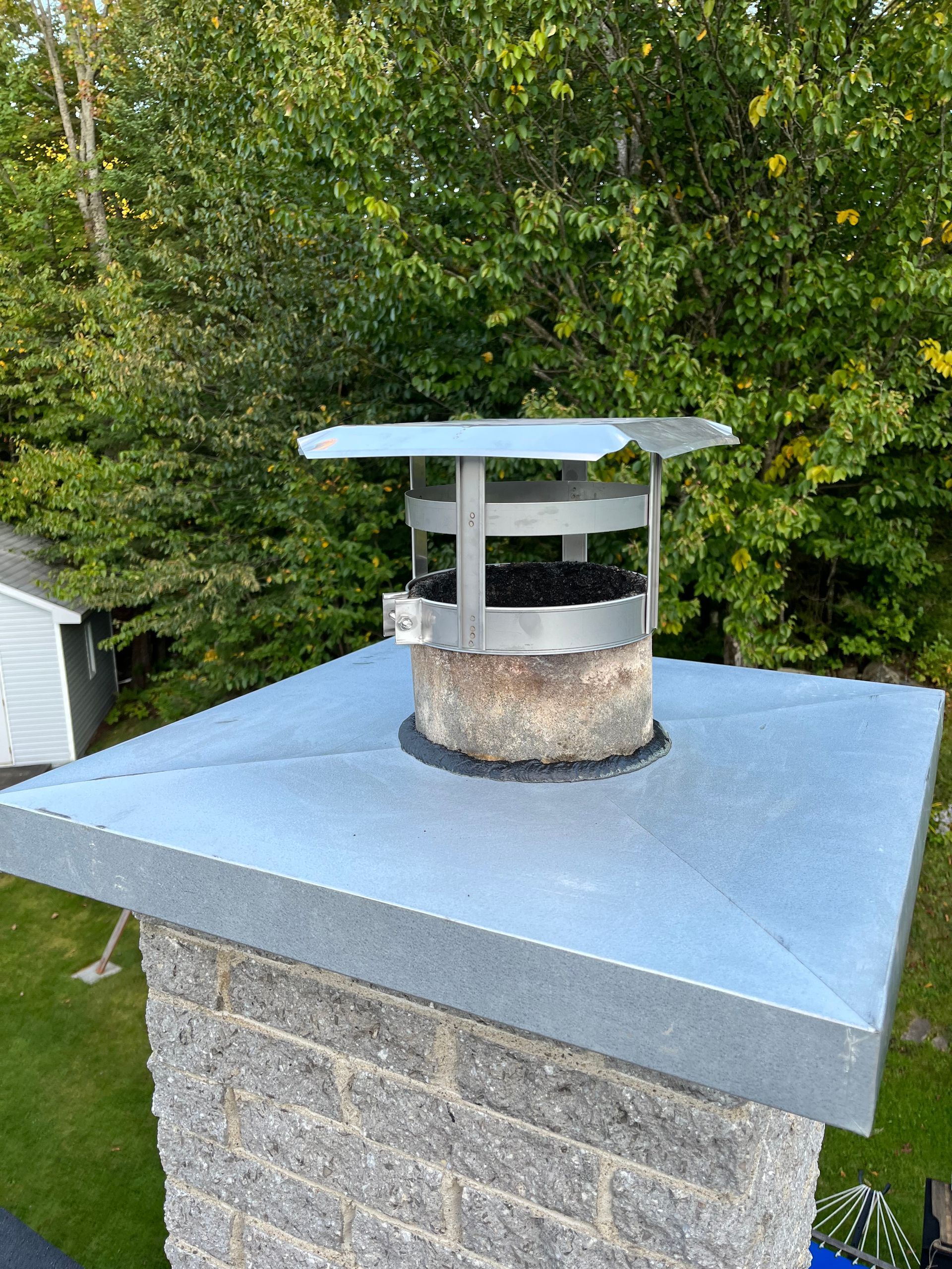 Une cheminée en brique surmontée d'un capuchon en métal.
