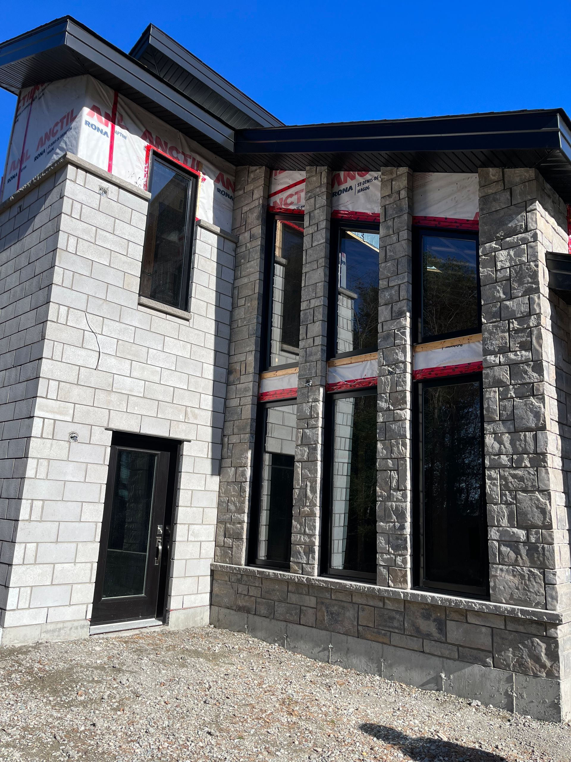 Une grande maison en briques blanches avec de nombreuses fenêtres est en construction.