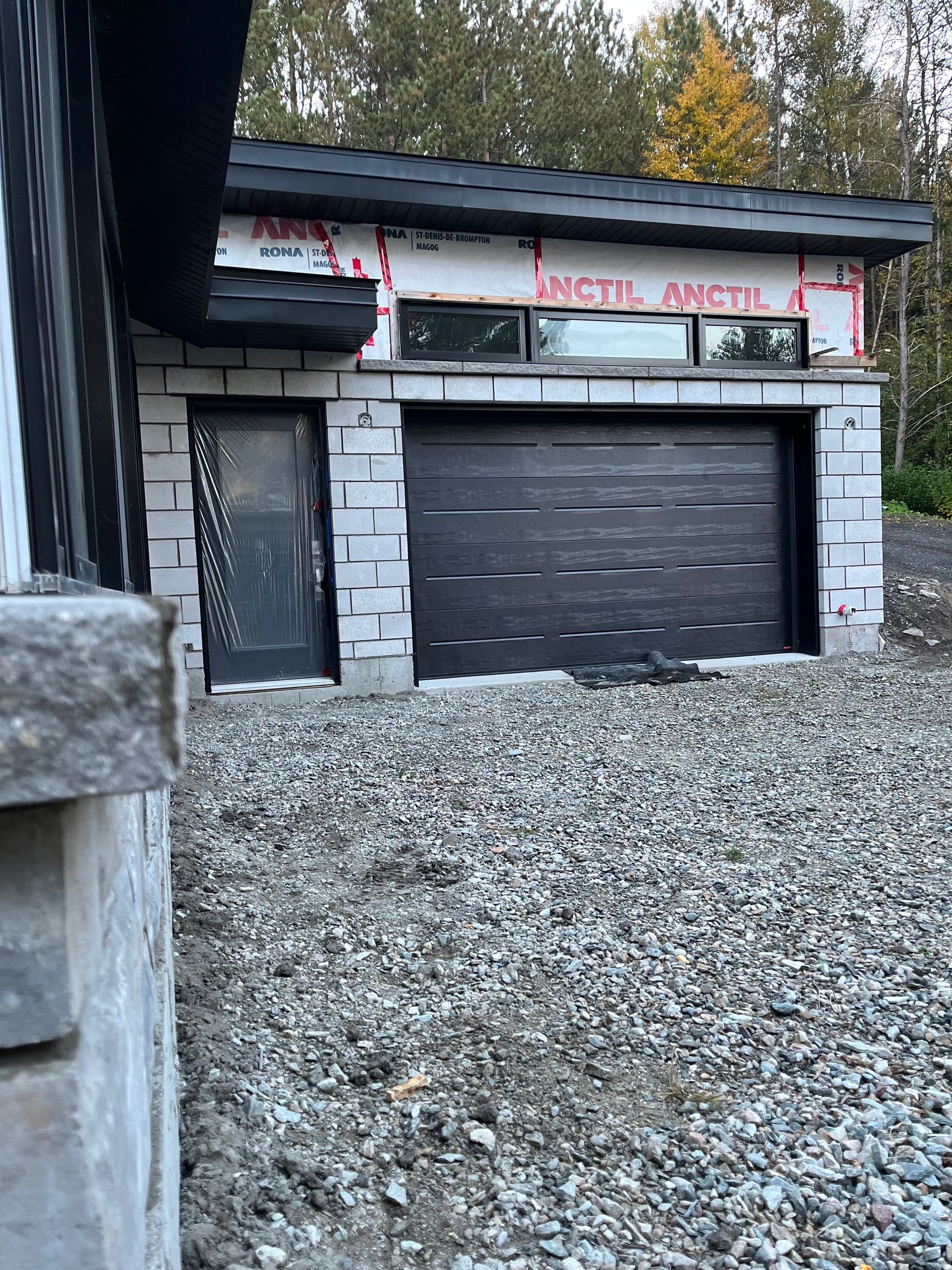 Une porte de garage est en cours d'installation sur le côté d'une maison.