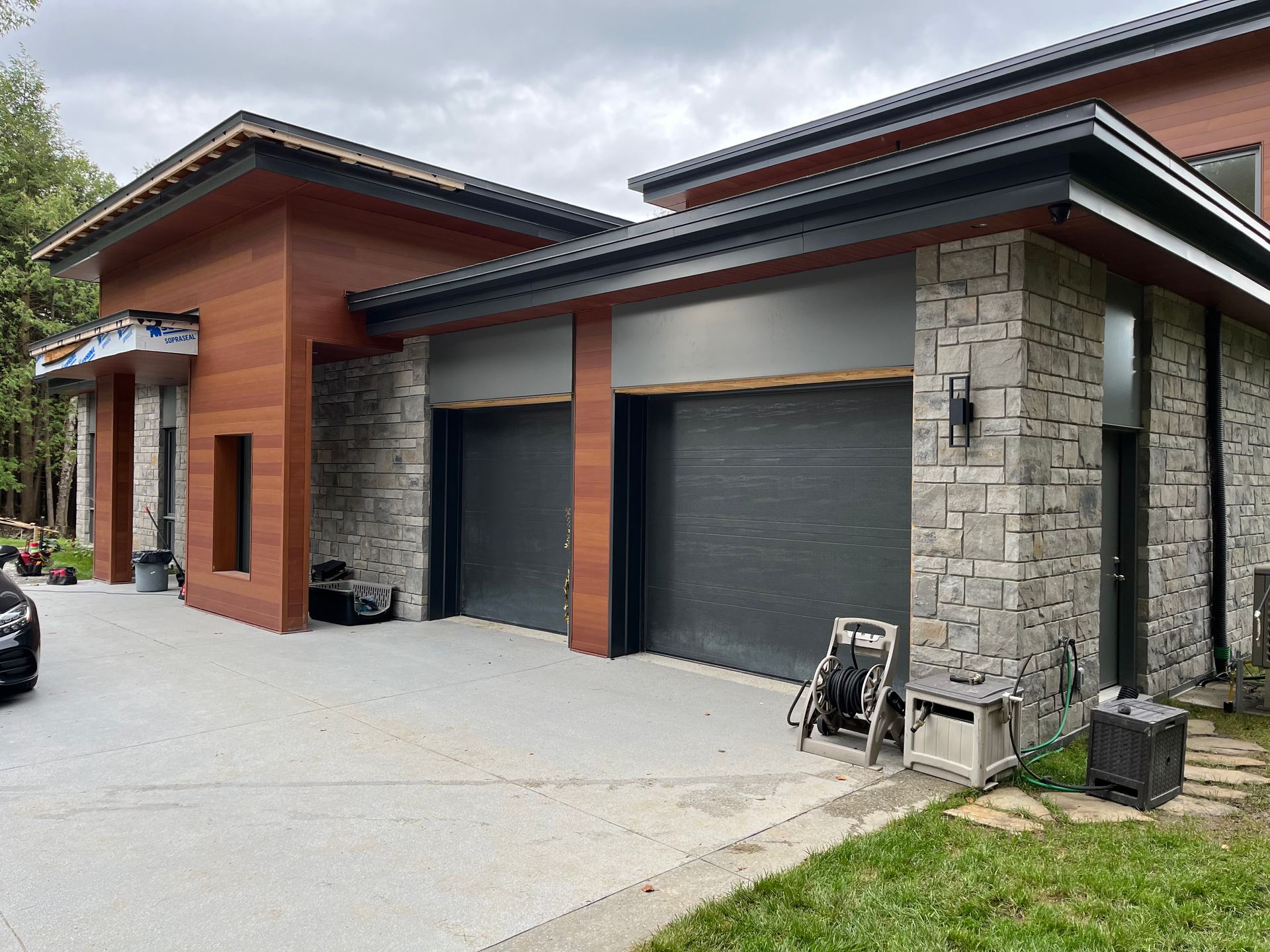 Une grande maison avec deux portes de garage et une voiture garée devant.