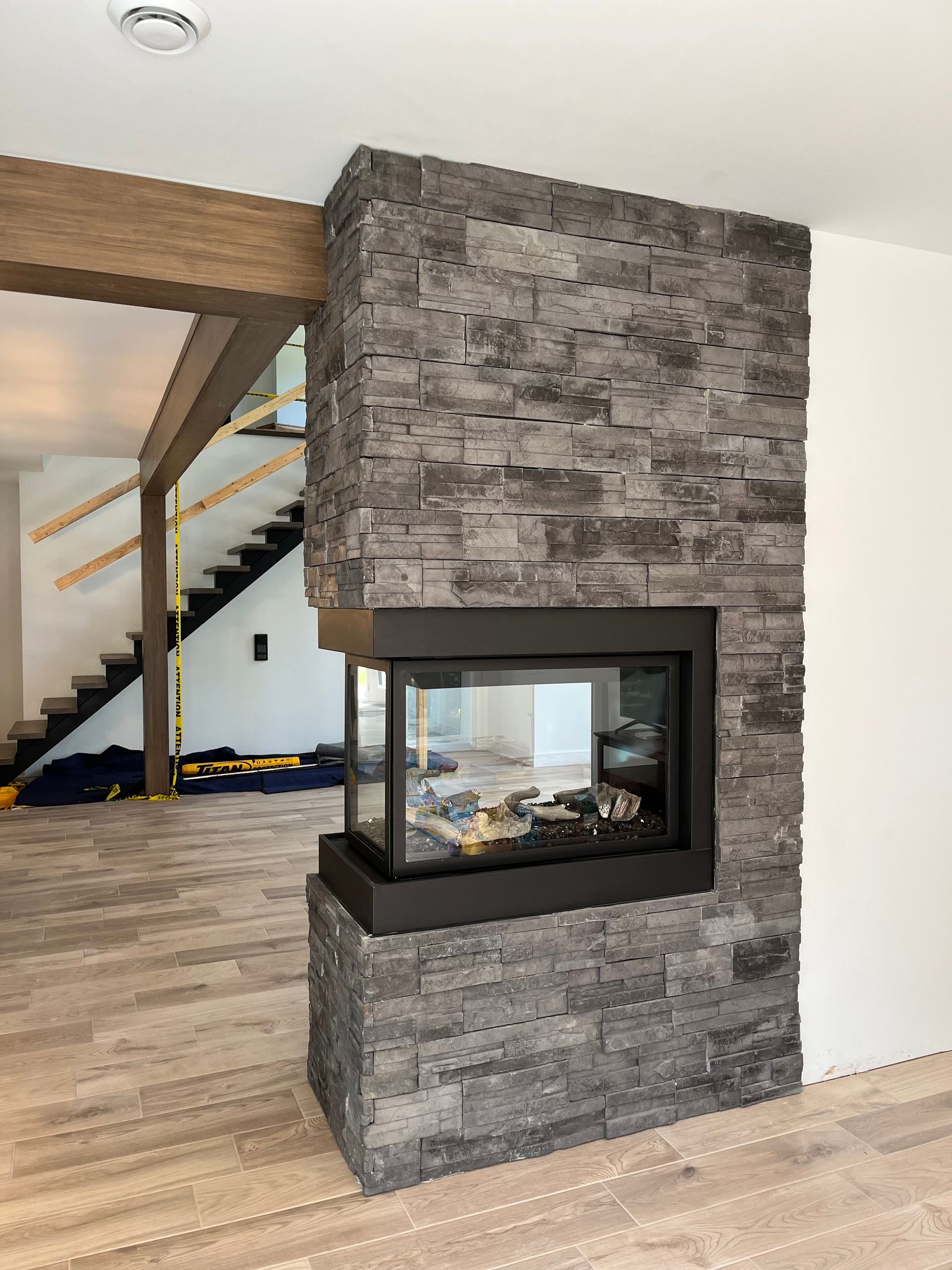 Une cheminée dans un salon avec un escalier en arrière-plan.