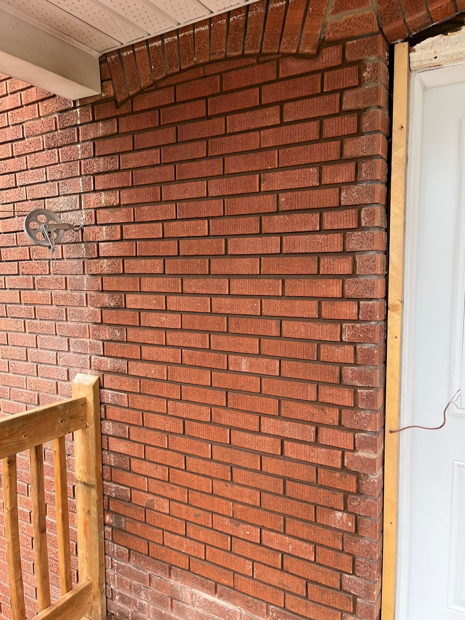Un mur de briques rouges avec une porte et une balustrade blanches.