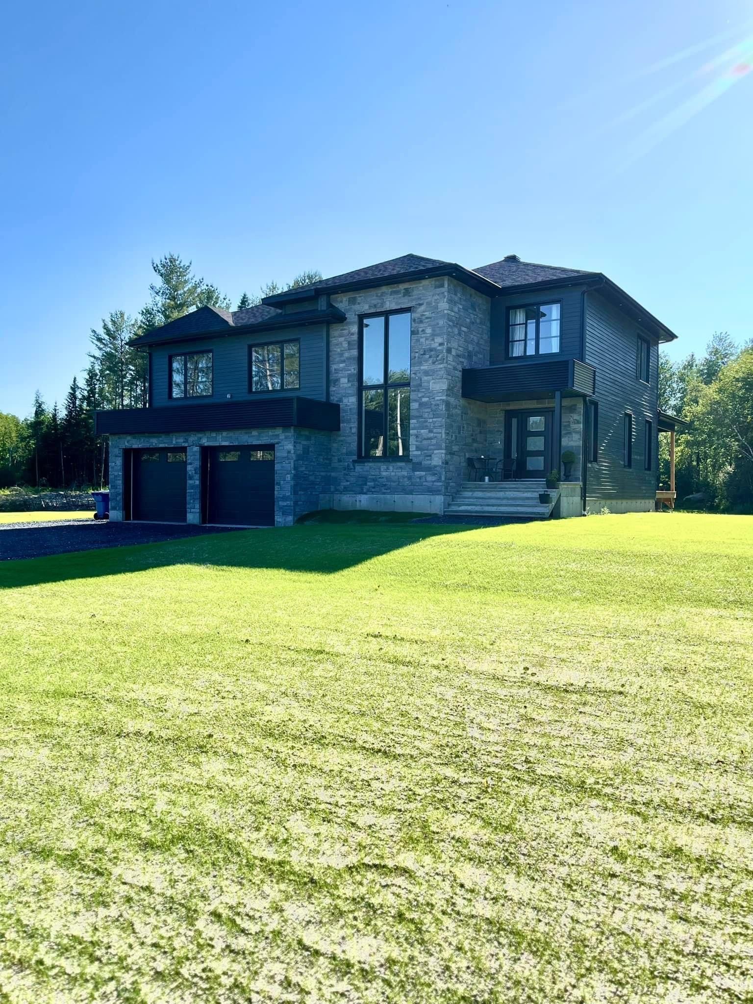 Une grande maison est située au sommet d’un champ verdoyant.