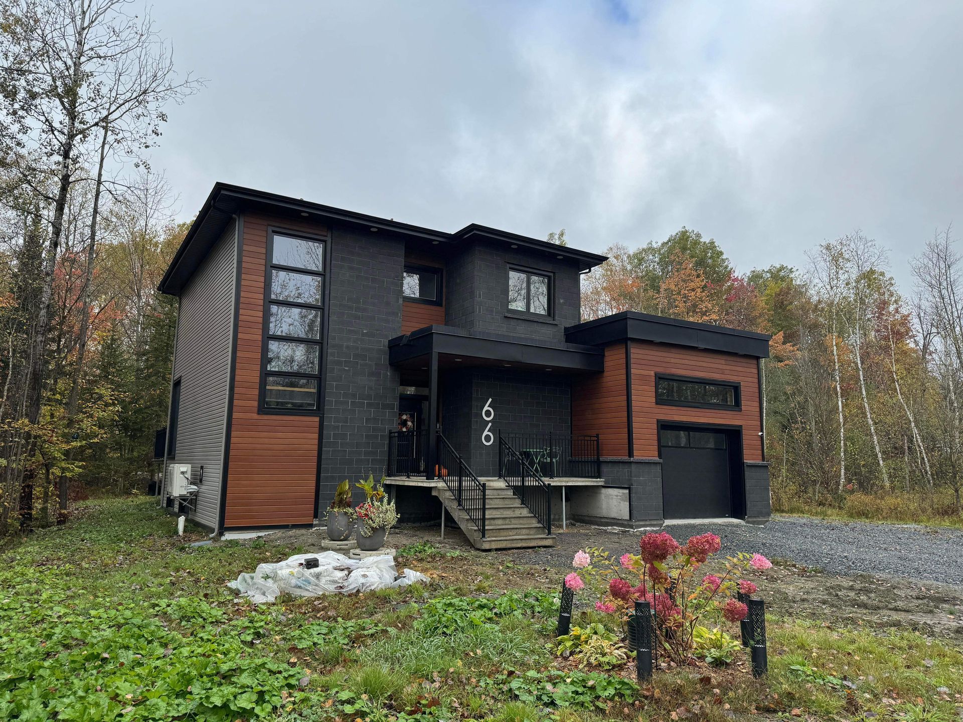 Une grande maison est située au milieu d’un champ verdoyant entouré d’arbres.