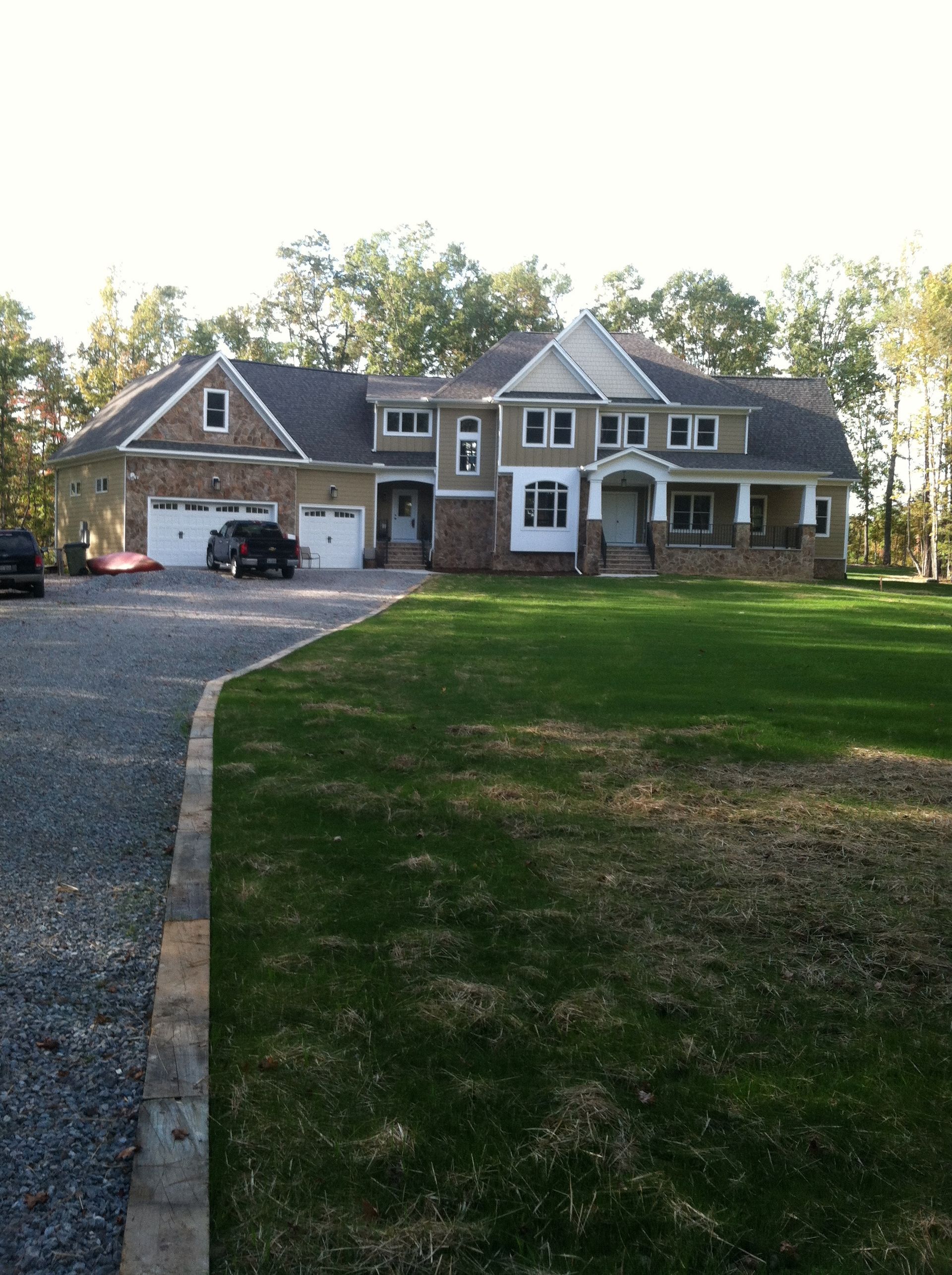 Large suburban brick house with a garage, front porch, and a wide driveway beside a green lawn.
