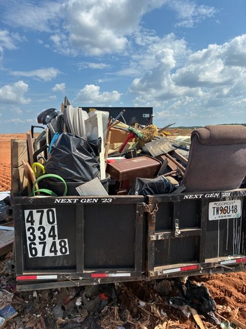 Construction debris piled in a dumpster trailer under a cloudy sky.