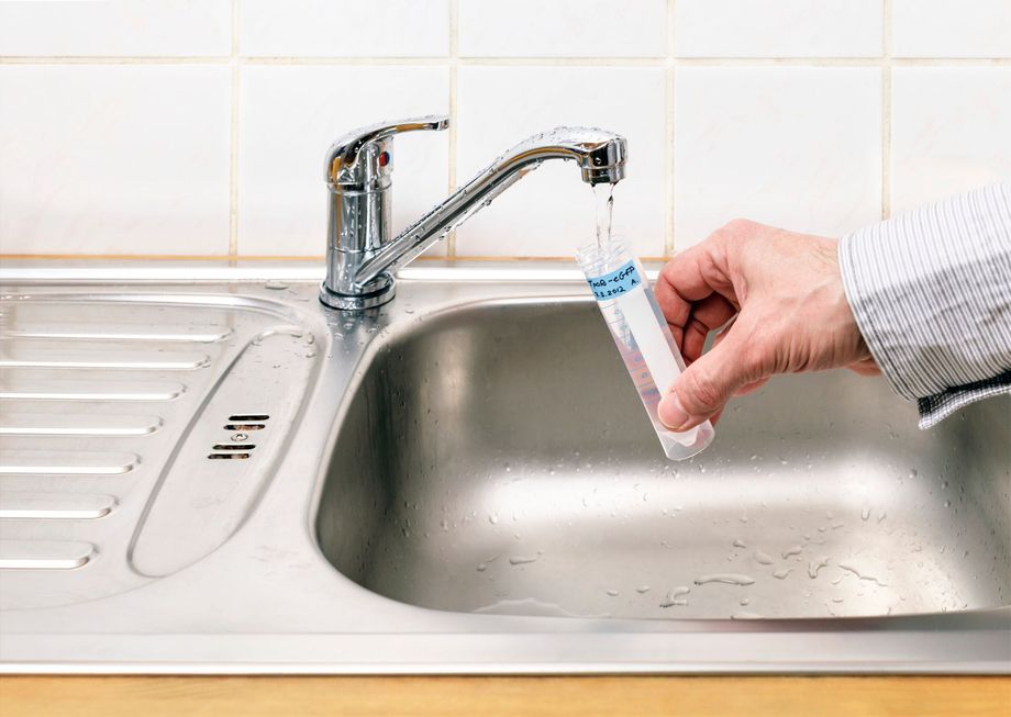 Una persona sta prelevando un campione d'acqua dal rubinetto del lavandino della cucina.