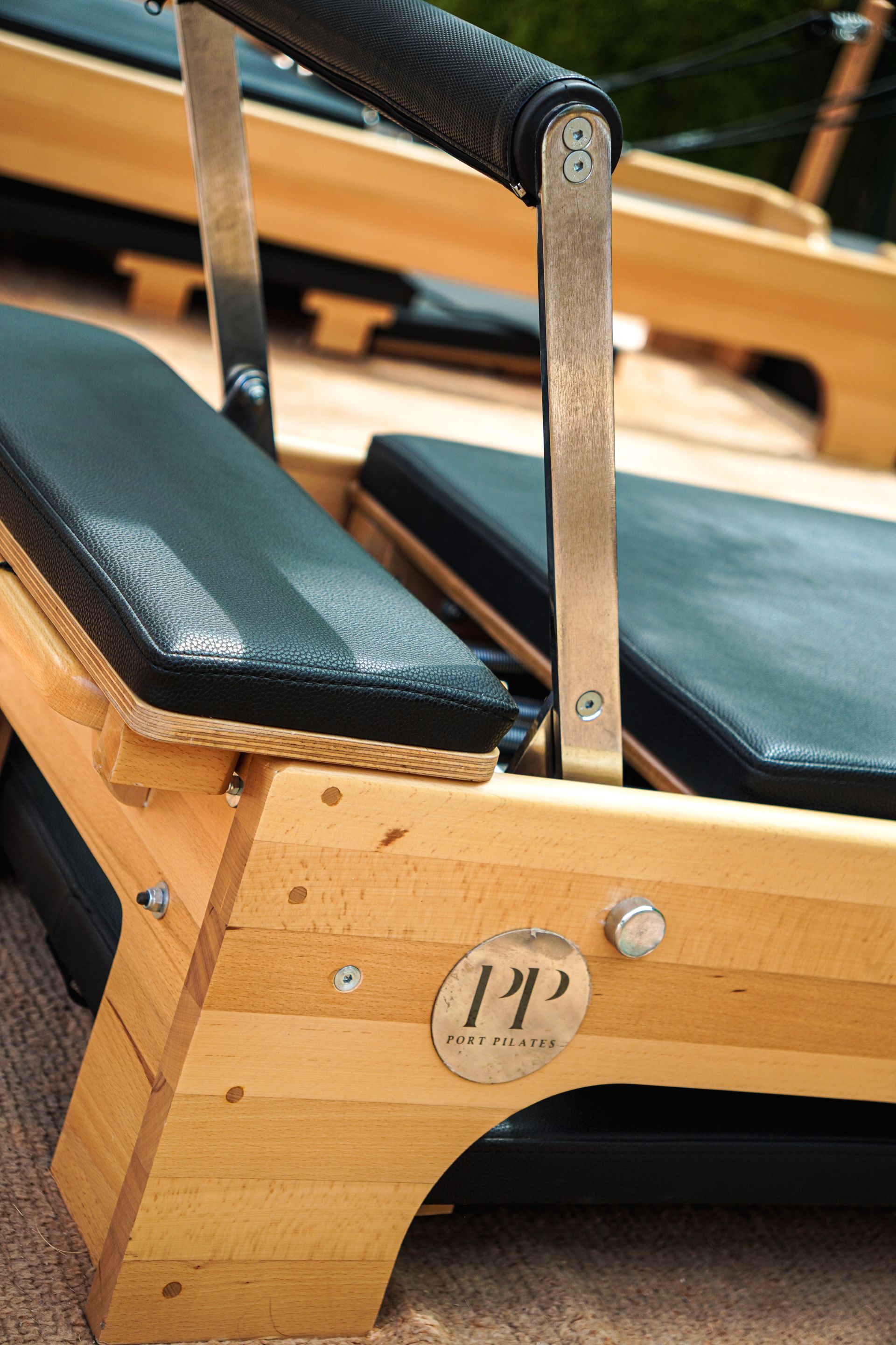 Houten reformer met zwarte kussens en armleuningen, close-up