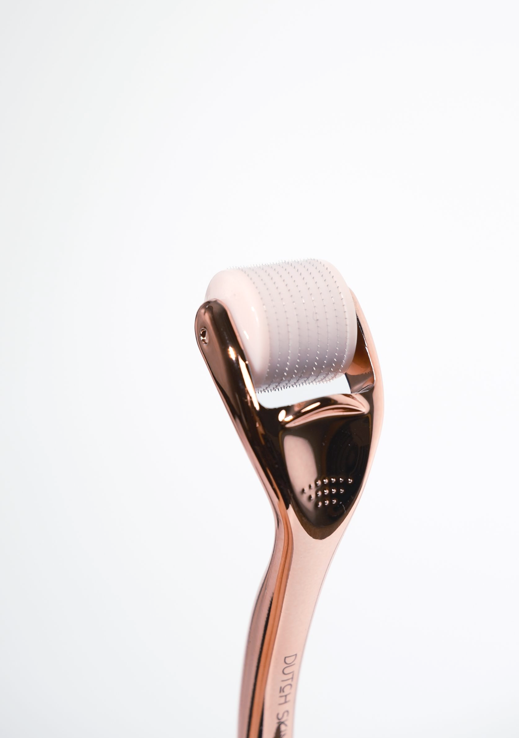Roségouden gezichtsroller met een witte, gestructureerde rollerkop op een witte achtergrond.