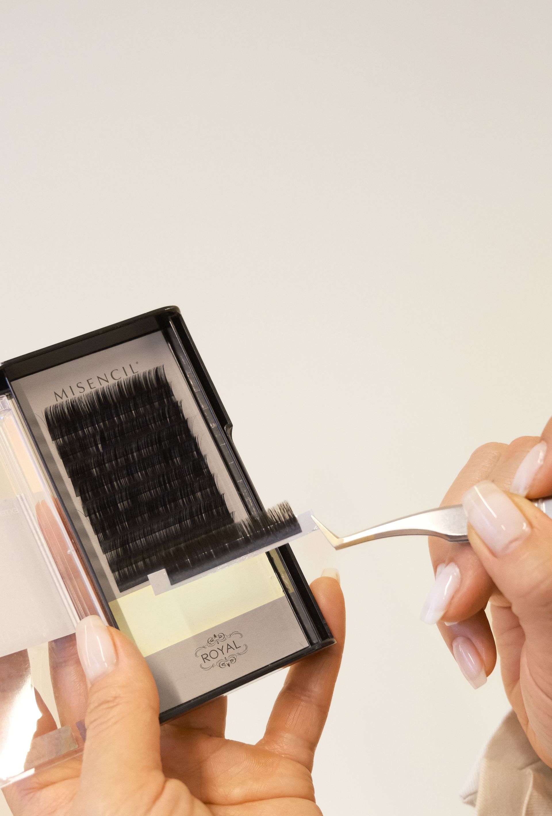 Handen houden een doosje met wimperextensions vast. 