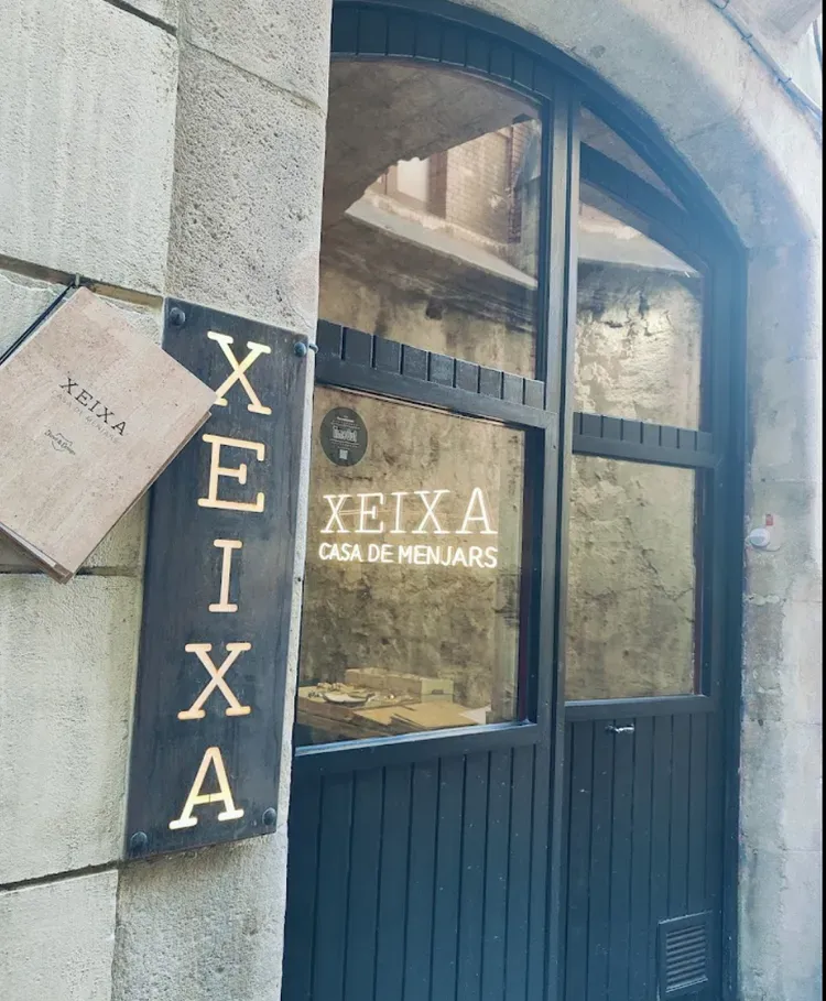 Blue arched doorway with a “XEIXA” sign and “Xeixá Casa de Xenerais” lettering on the glass.