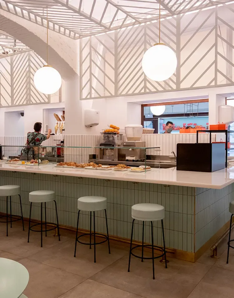 Modern café interior with white pendant lights, a marble counter, and bar stools