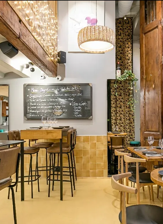 Cozy café interior with wooden tables, high stools, chalkboard menu, and warm pendant lighting