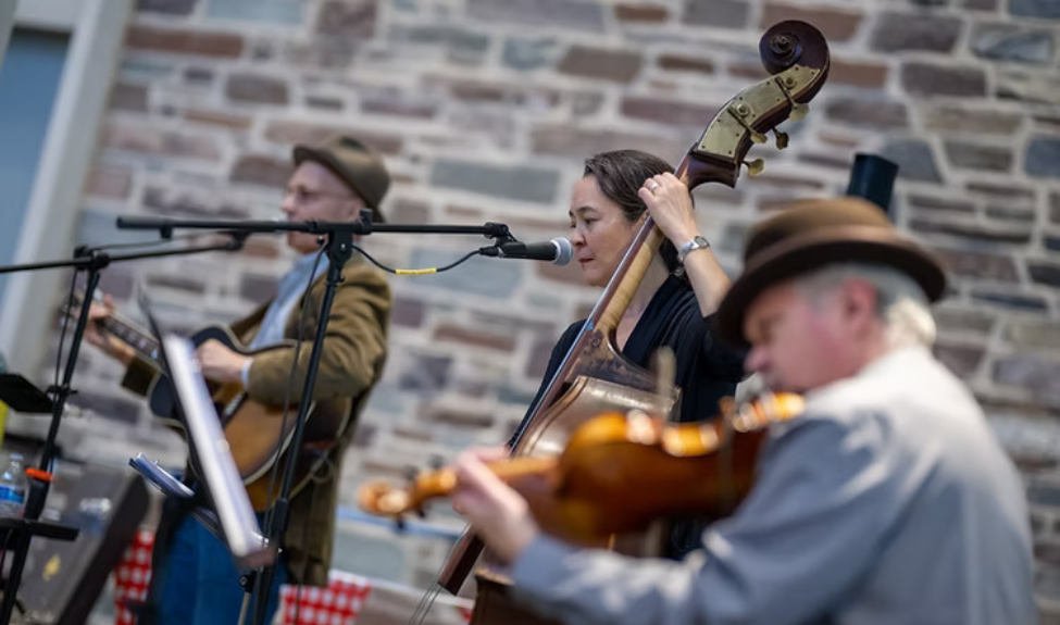 The American roots band the Ragtime Relics performing outdoors against the backdrop of a stone building.