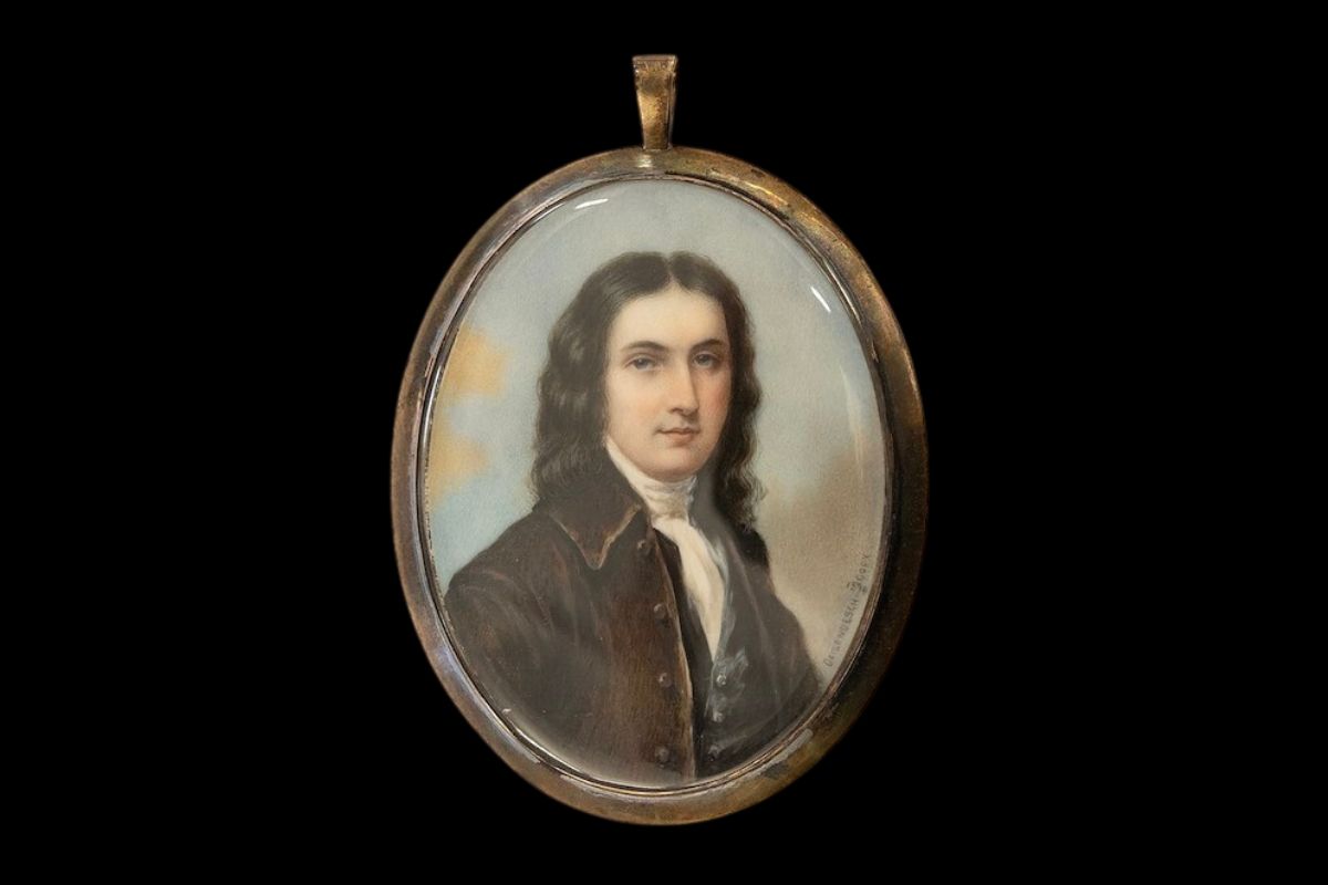 Oval miniature portrait of a man with dark curly hair in a brown coat, set in a gold pendant frame