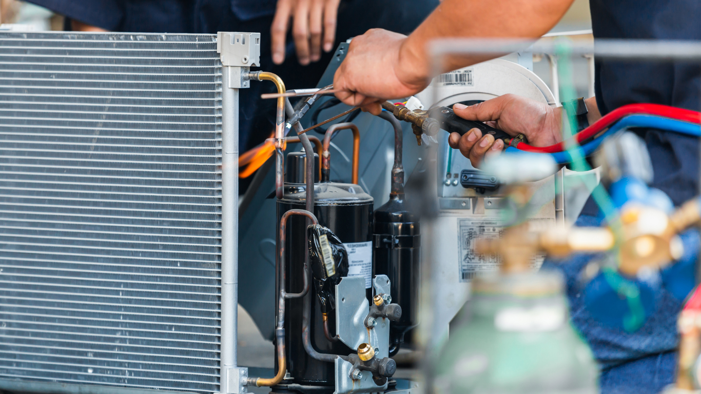 Technician using tools to repair an HVAC unit with exposed wiring and metal components