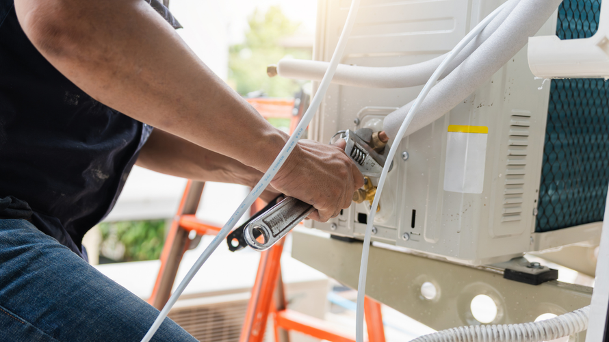 Technician using a wrench to service outdoor HVAC equipment on a truck-mounted platform