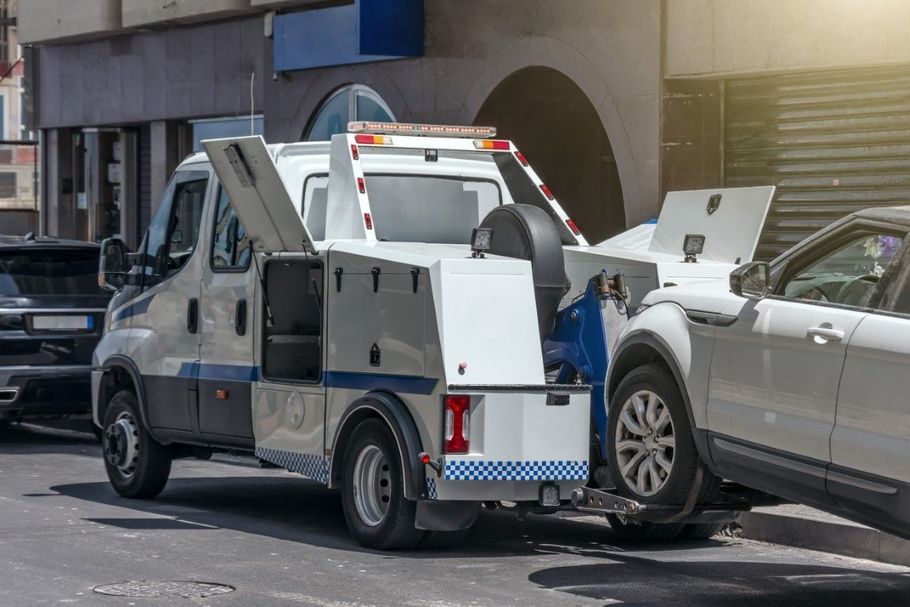 Tow truck loading a silver sedan on a city street after a crash
