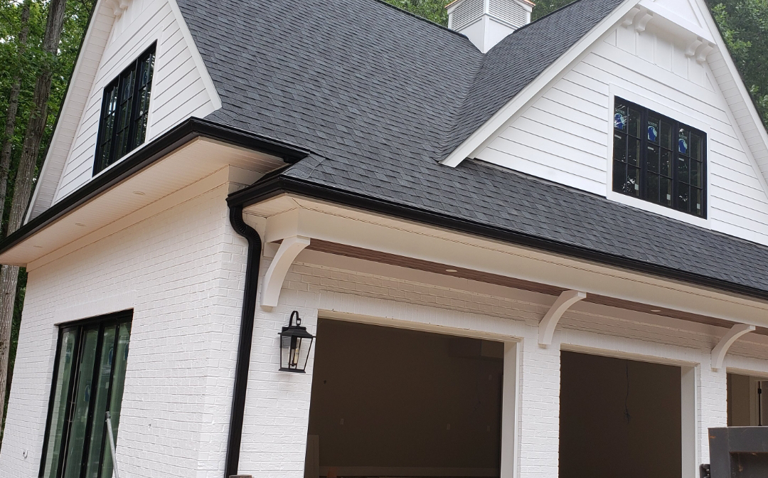 White two-car garage with black roof, trim, and windows. A lantern hangs above the garage doors.