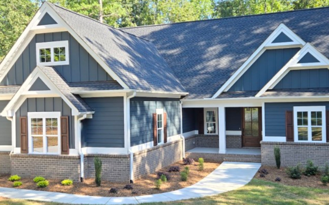 Blue house with white trim and brown shutters, brick base, and walkway.