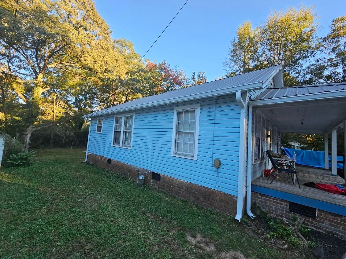 Light blue house with white trim, metal roof, and covered porch on a sunny day.