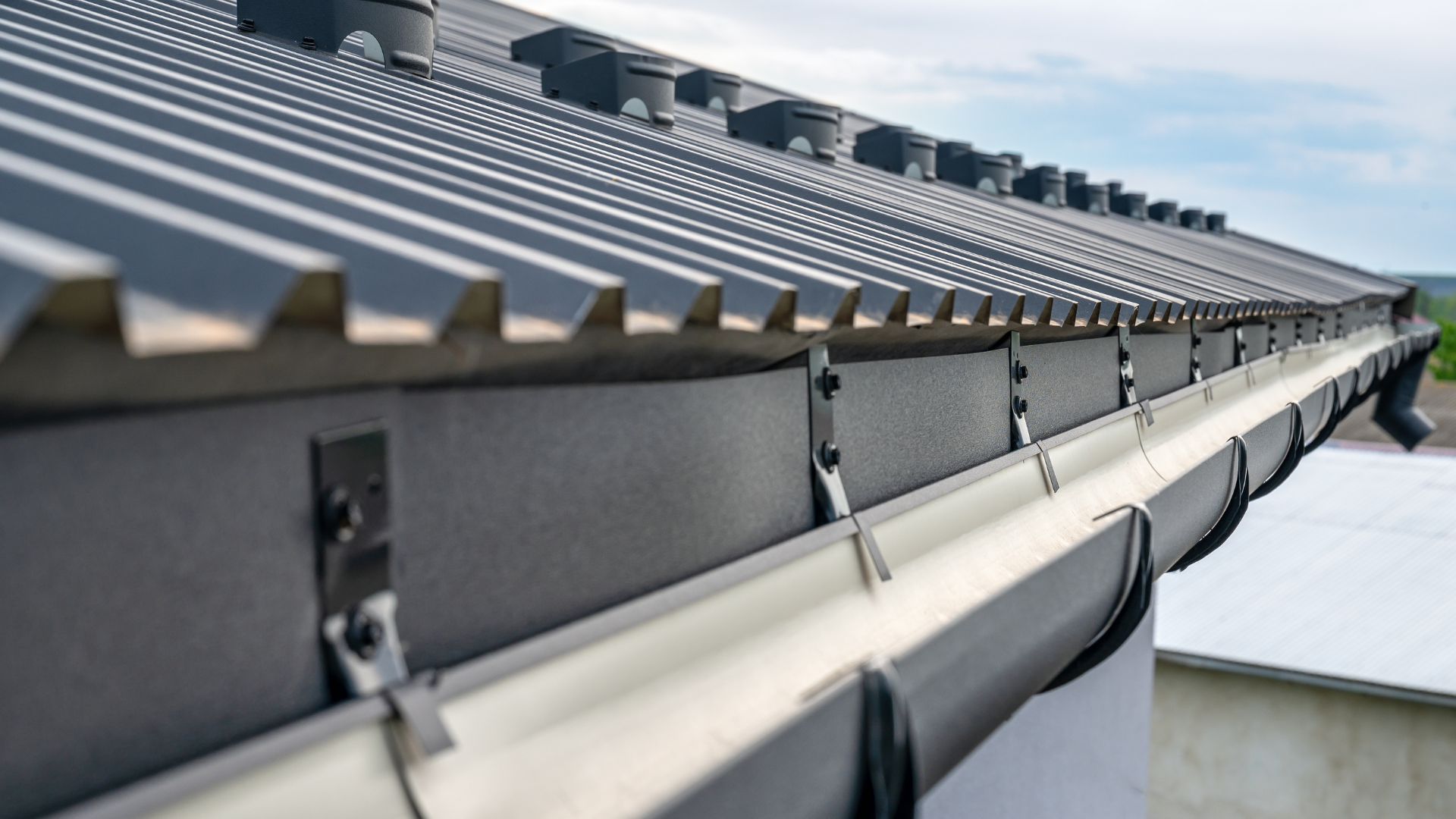 Gray metal roof with matching gutter system, viewed from a low angle.