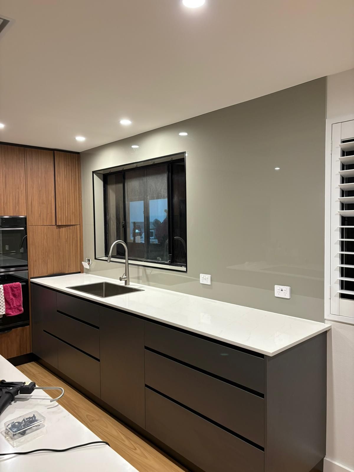 Modern kitchen with gray cabinets, white countertop, stainless steel sink, and gray backsplash.