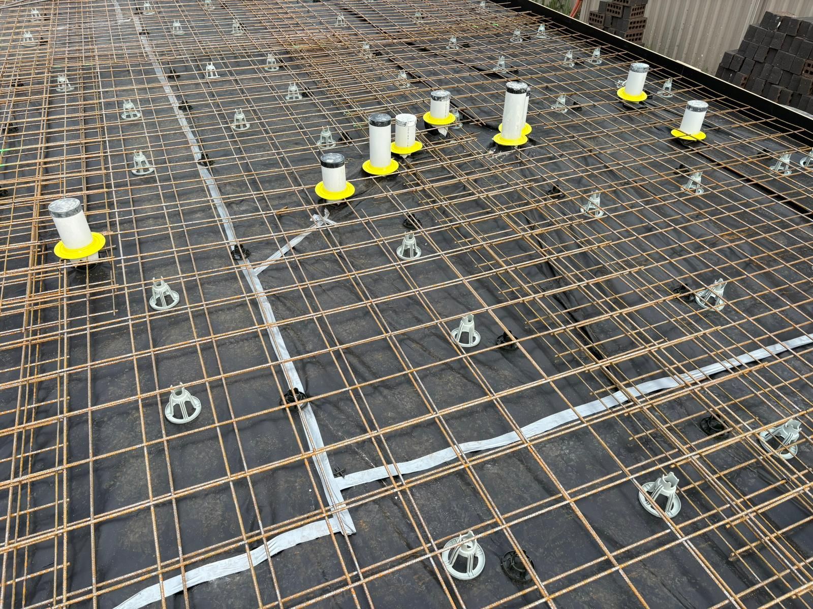 Reinforced concrete structure with mesh, pipes, and supports, ready for pouring.