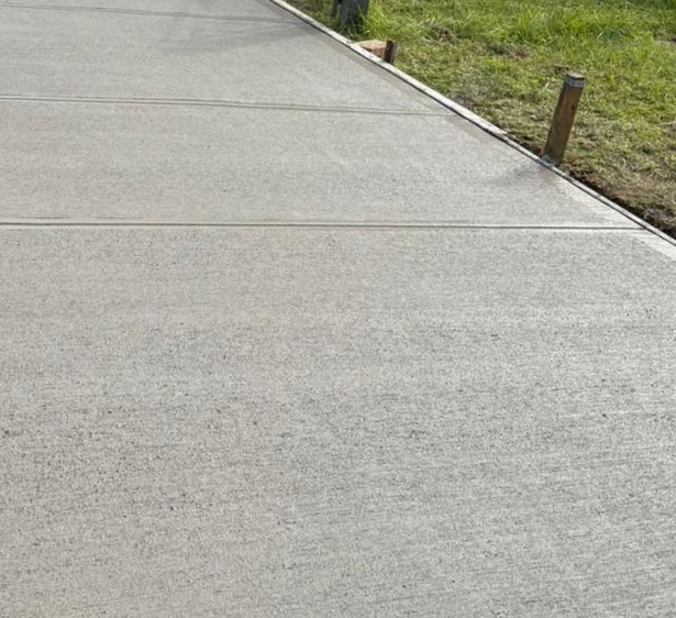 Newly poured concrete sidewalk with expansion joints next to grass.