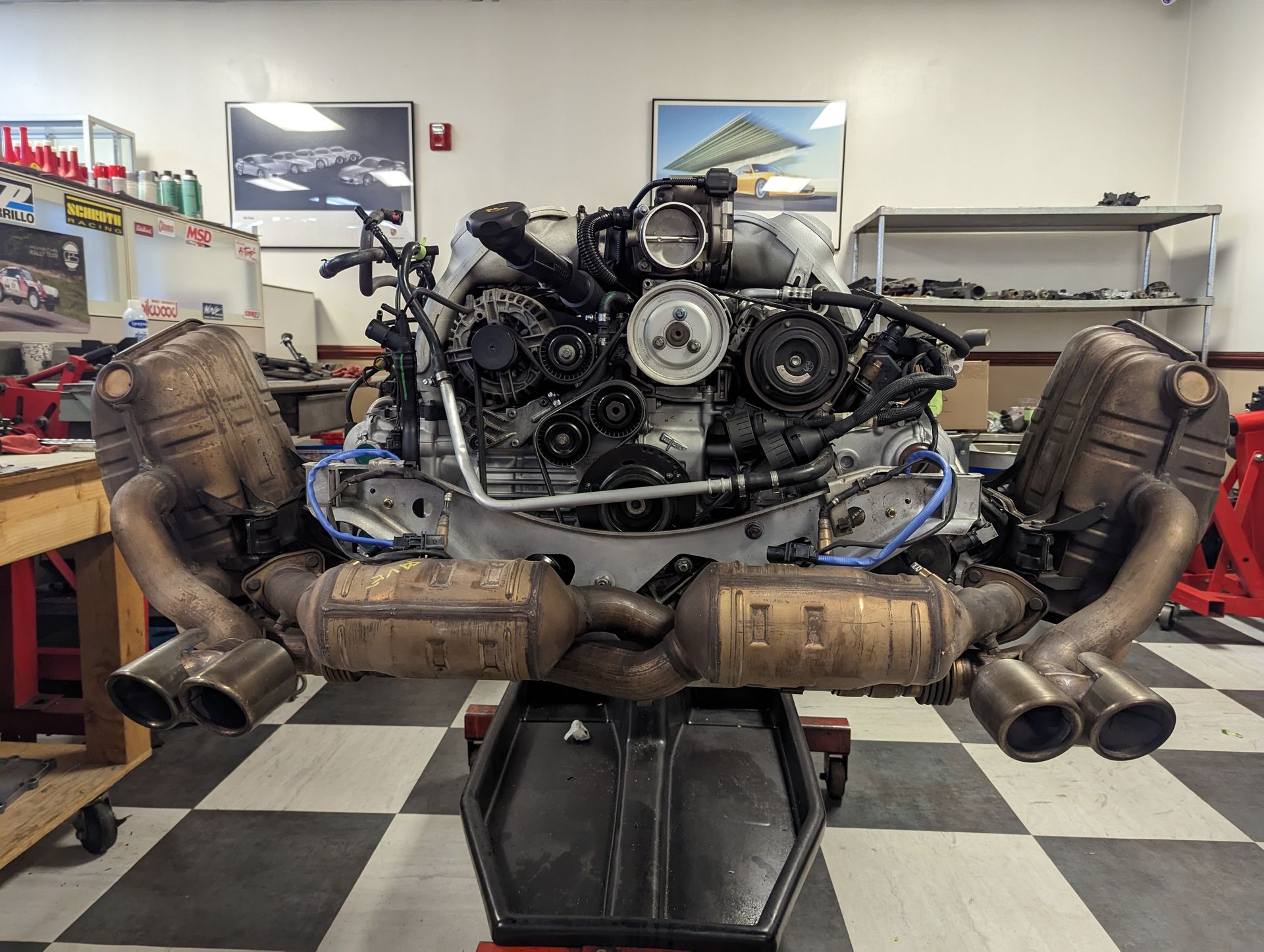 Porsche engine assembly on a shop stand with exhaust components attached. | Autobahn Performance Inc