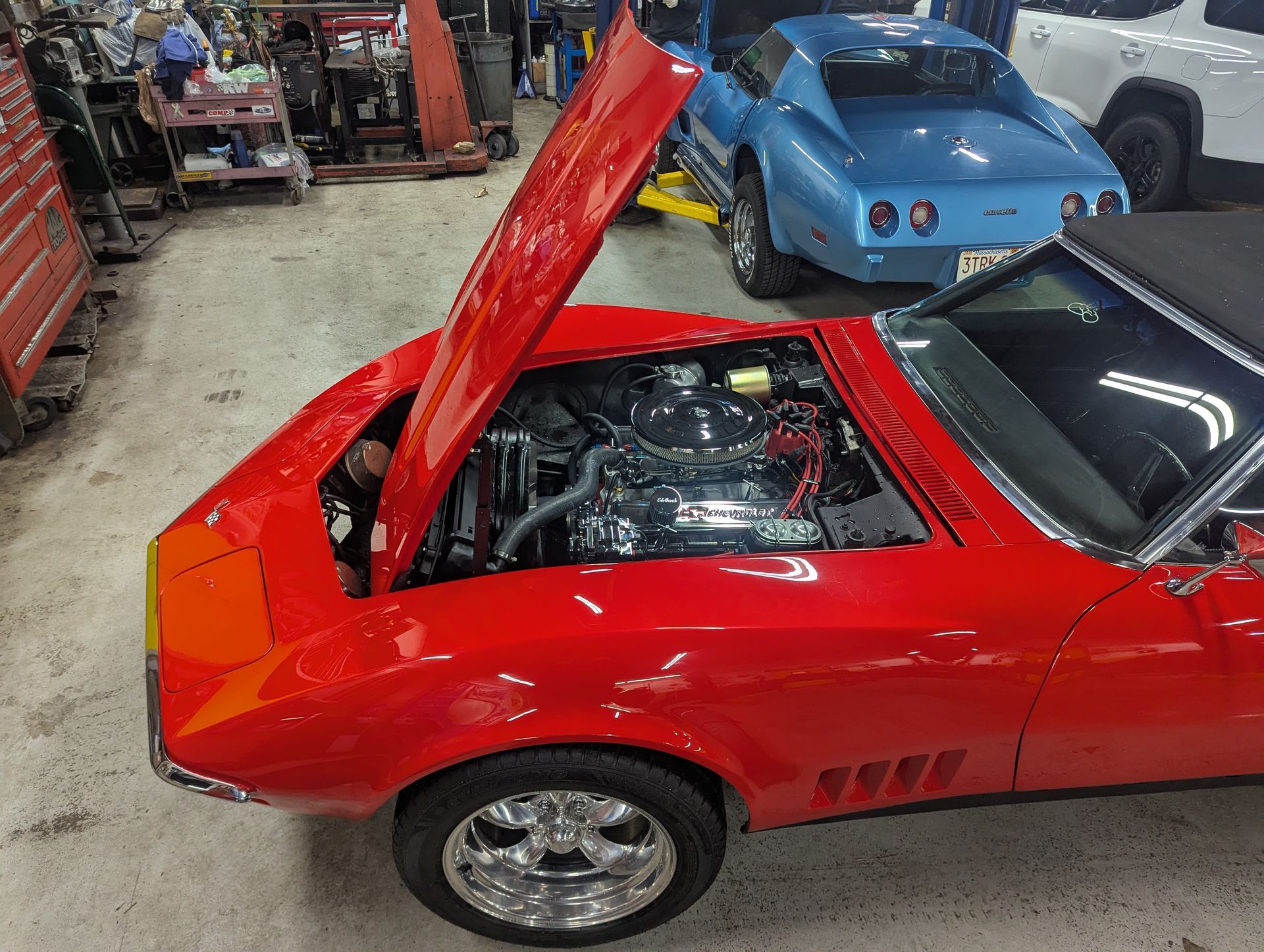 Red convertible with hood open, showing engine in a garage with a blue c | Autobahn Performance Incar in the background.
