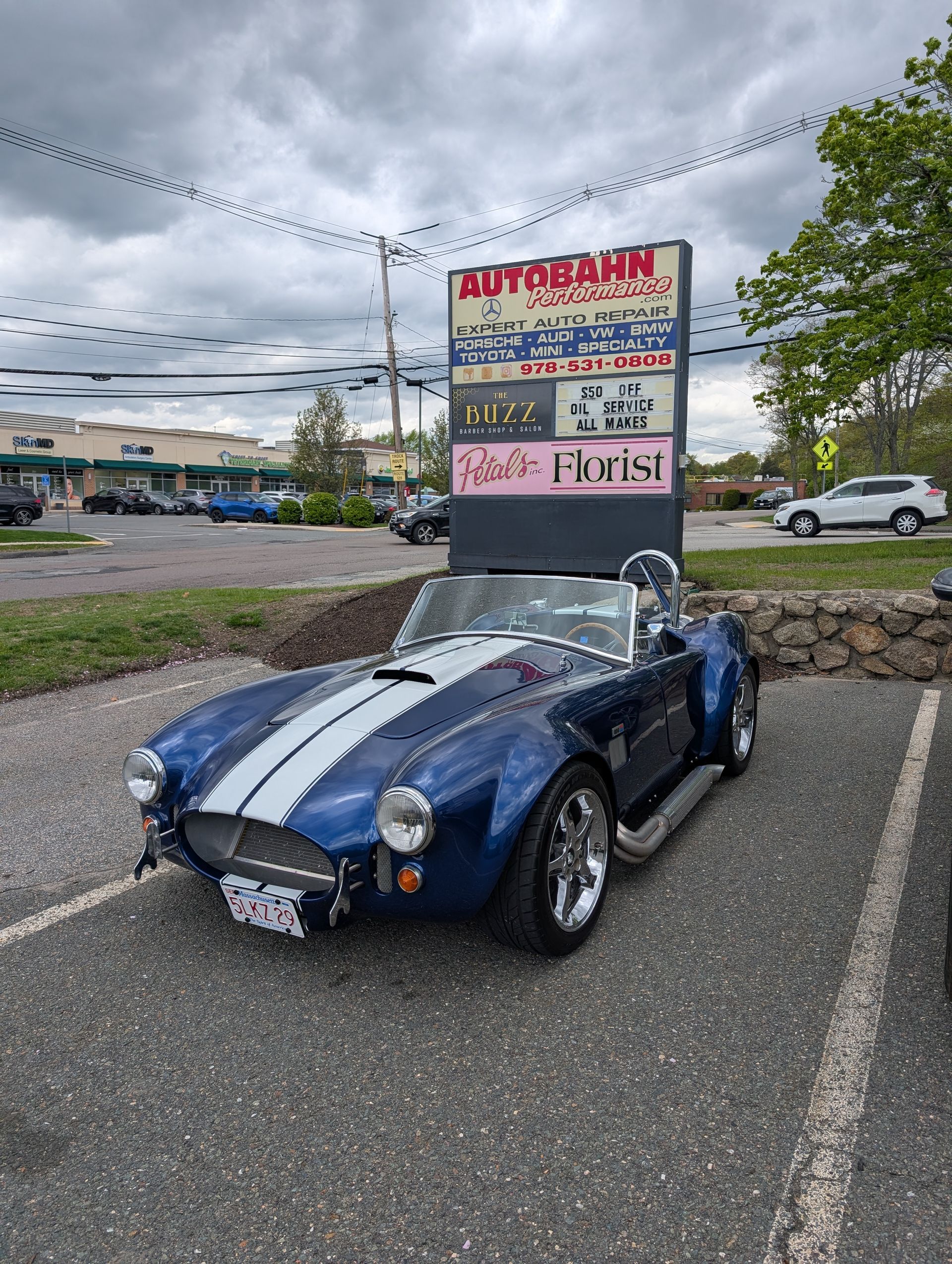 Blue Shelby Cobra roadster parked in front of a shopping center sign. | Autobahn Performance Inc