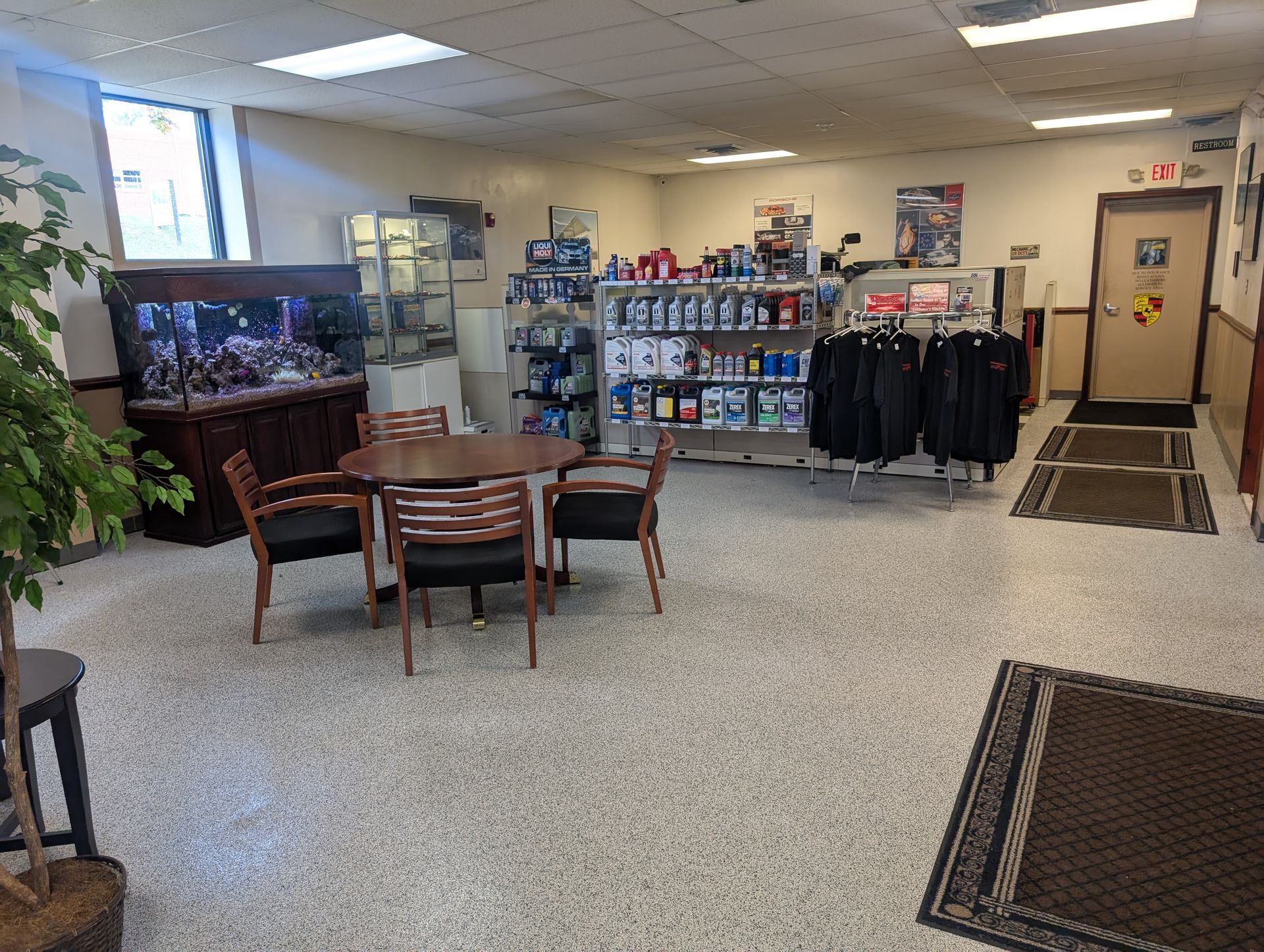 Interior of a shop with an aquarium, round table with chairs, and merchandise on shelves and racks. | Autobahn Performance Inc