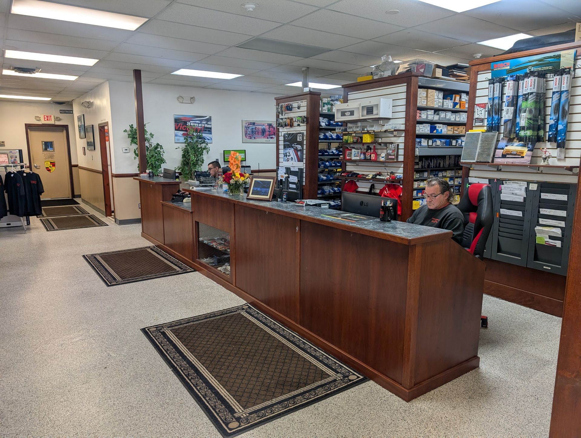Inside view of an auto parts store's counter and shelving. A man sits behind the counter, while merchandise is visible. | Autobahn Performance Inc