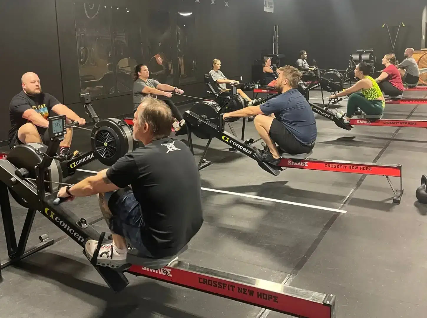 A group of people are rowing rowing machines in a gym.