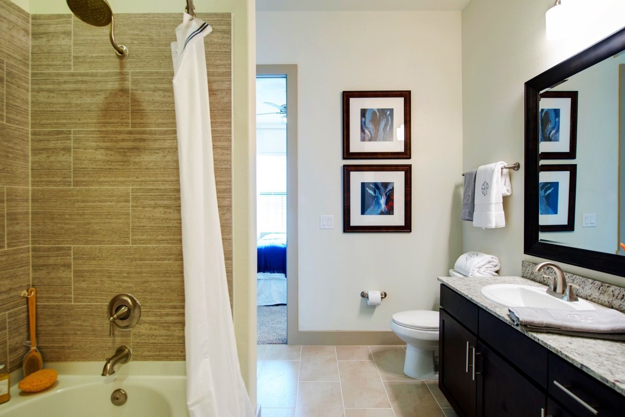 Bathroom featuring a tub/shower, toilet, and granite vanity in an apartment.