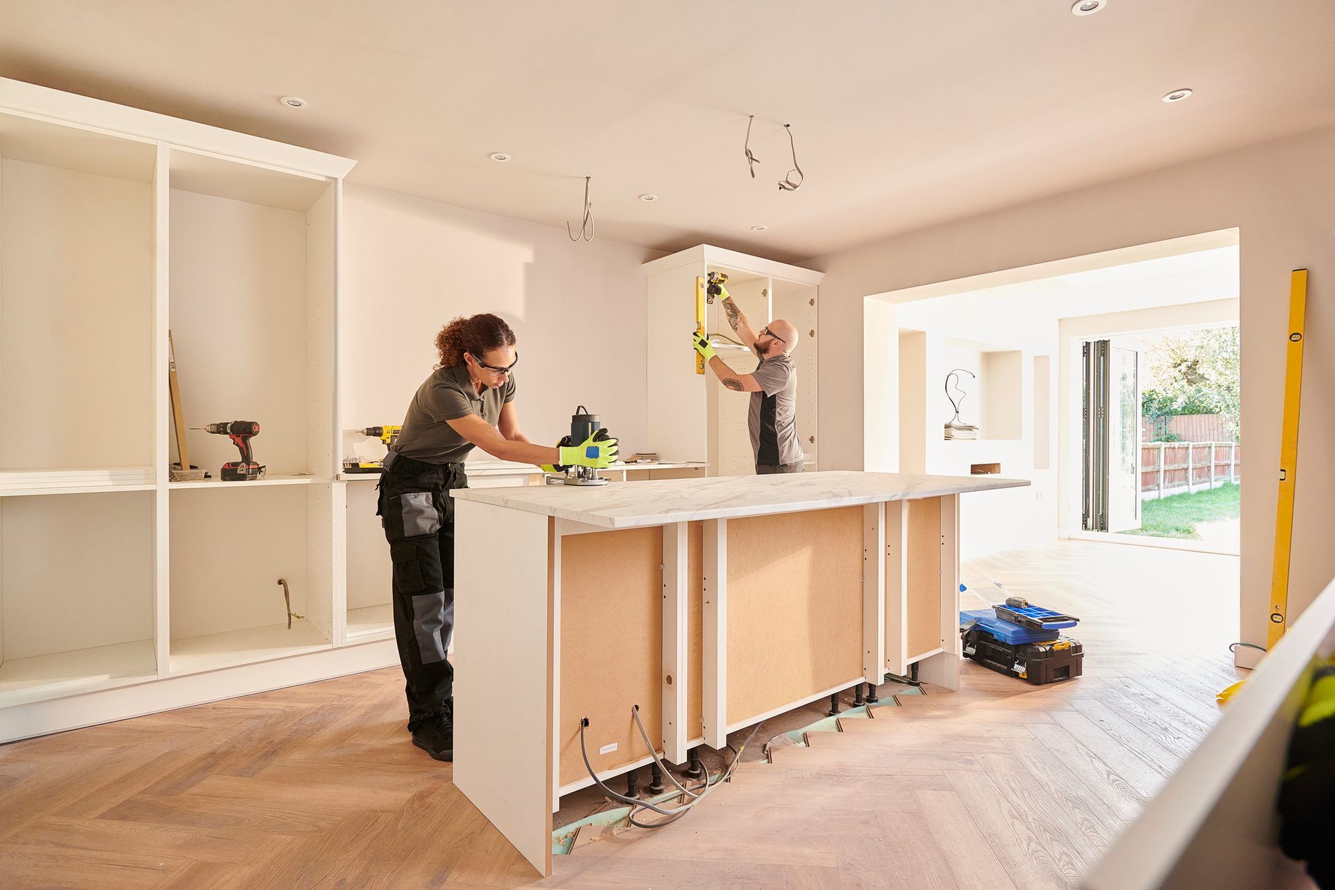 Two workers are remodeling a kitchen.